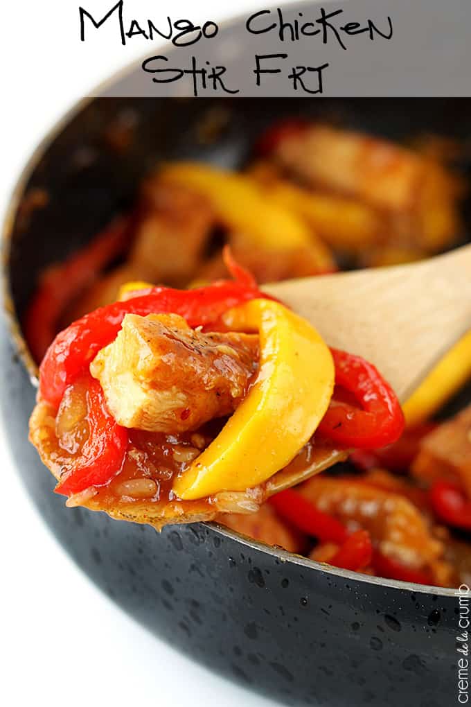 a wooden serving spoon holding a scoop of mango chicken stir fry with more chicken in a skillet faded in the background with the title of the recipe written on the top of the image.