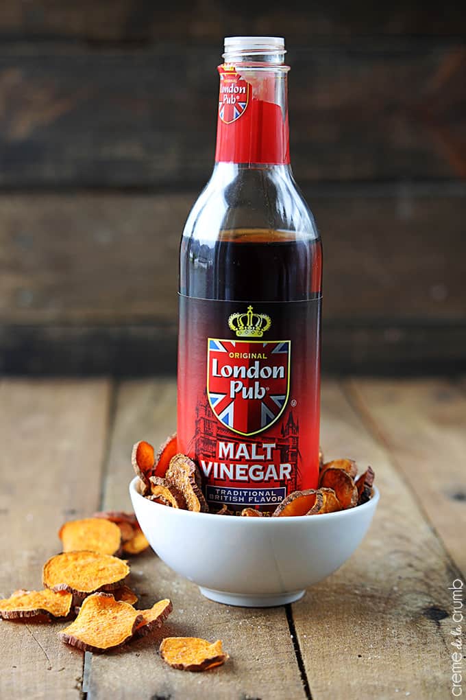 a bottle of malt vinegar in a bowl of salt & vinegar sweet potato chips.