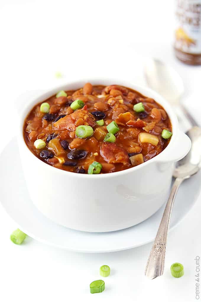 top view of smokey bbq baked beans in a bowl on a plate with a spoon.