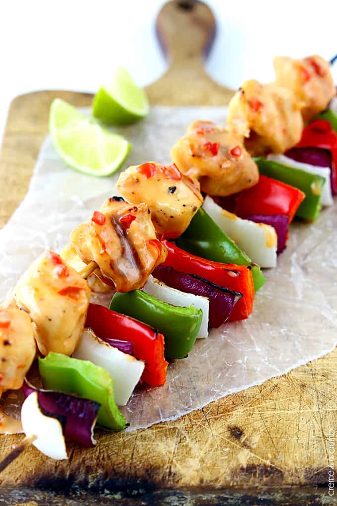 bang bang chicken kabobs on a wooden cutting board with slices of lime.