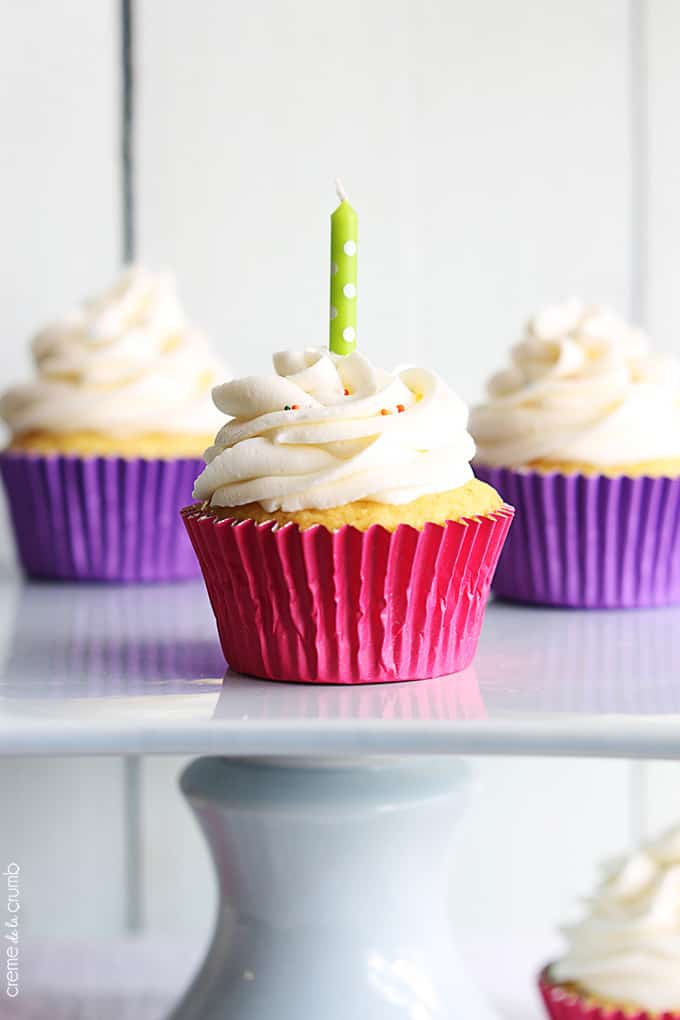 close up of birthday cake cupcakes in a pedestal cake tray with a candle in one of the cupcakes.