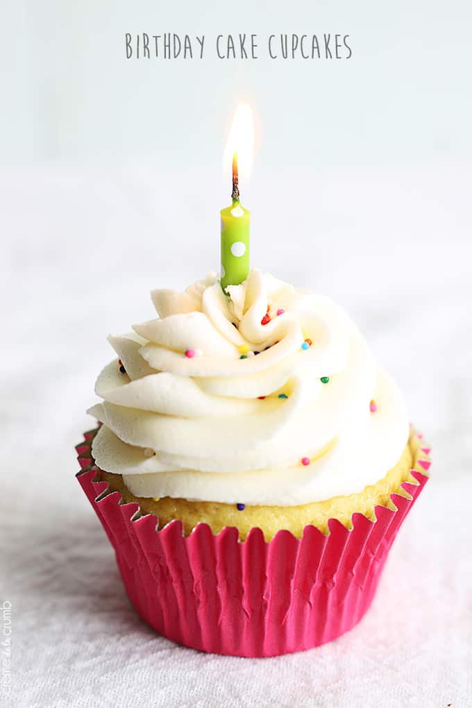 a birthday cake cupcake with a candle lit in it with the title of the recipe written on the top of the image.