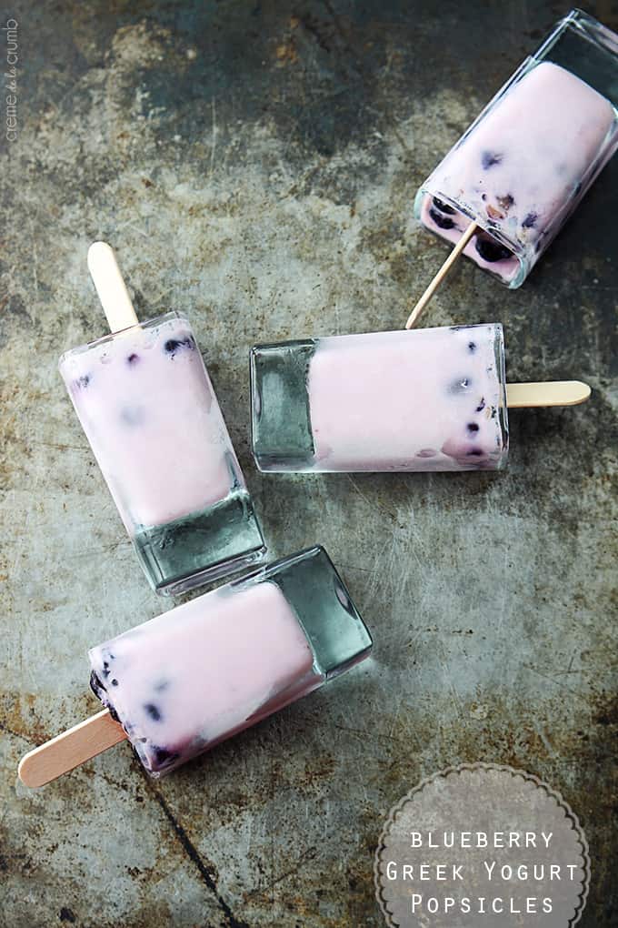 top view of blueberry Greek yogurt popsicles laying on their side with the title of the recipe written on the bottom right corner of the image.