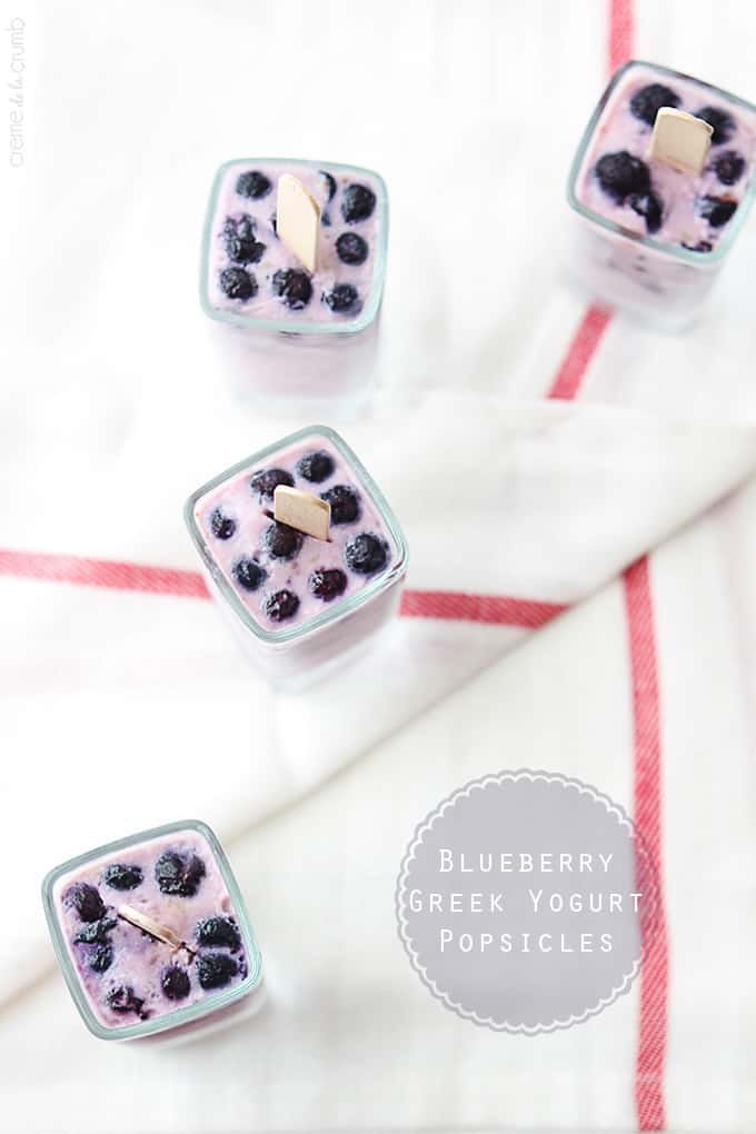 top view of blueberry Greek yogurt popsicles upside in glasses with the title of the recipe written on the bottom right corner of the image.