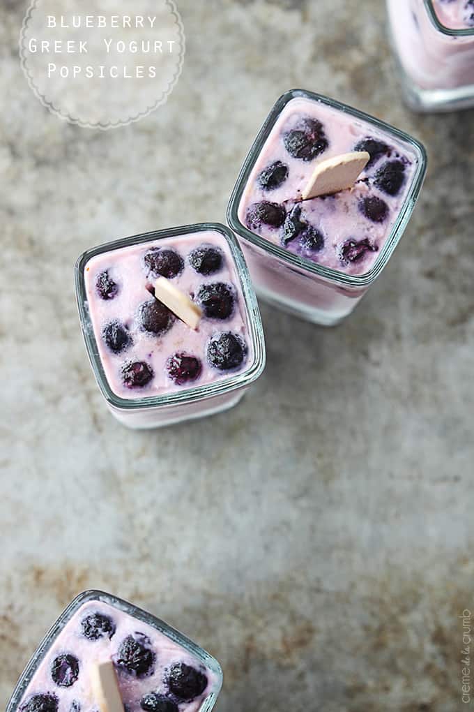 top view of blueberry Greek yogurt popsicles upside down in glasses with the title of the recipe written on the top left corner of the image.