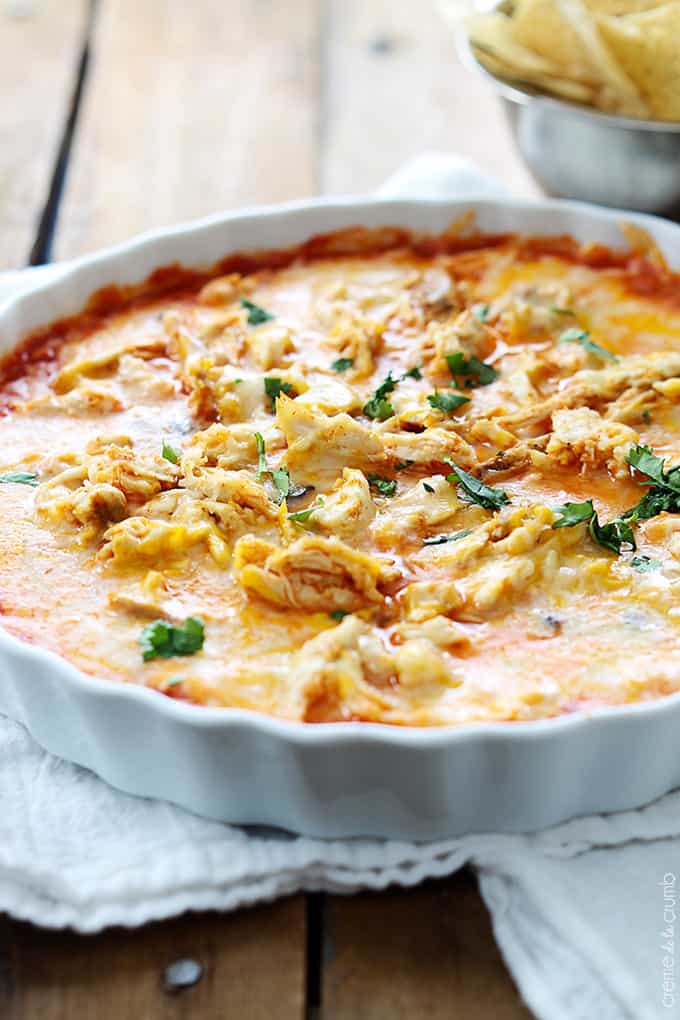 chicken enchilada dip in a serving dish with chips in the background.