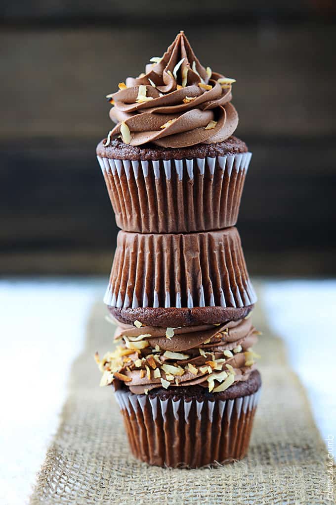 stacked chocolate coconut cupcakes on a burlap table runner.
