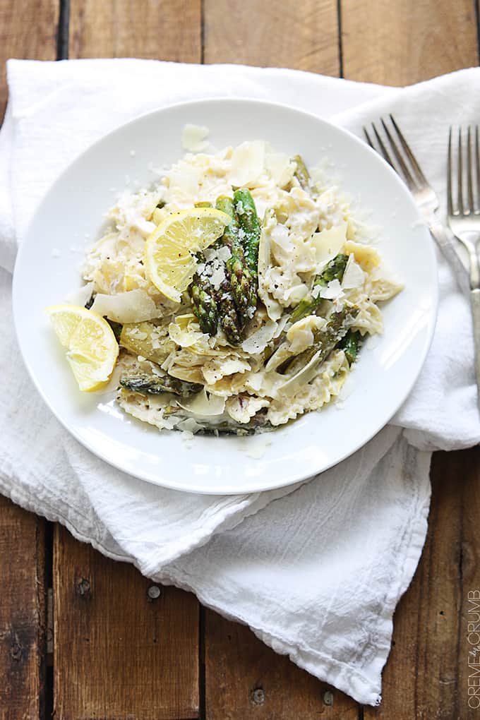 top view of lemon artichoke & asparagus pasta on a plate on a whit cloth napkin with two forks.