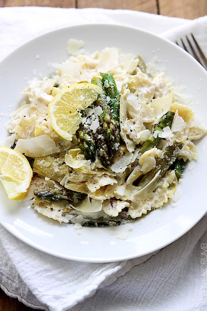 lemon artichoke & asparagus pasta on a plate on a white cloth napkin.