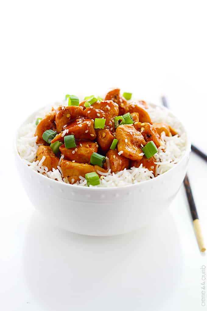 orange chicken on rice in a bowl with chopsticks on the side.