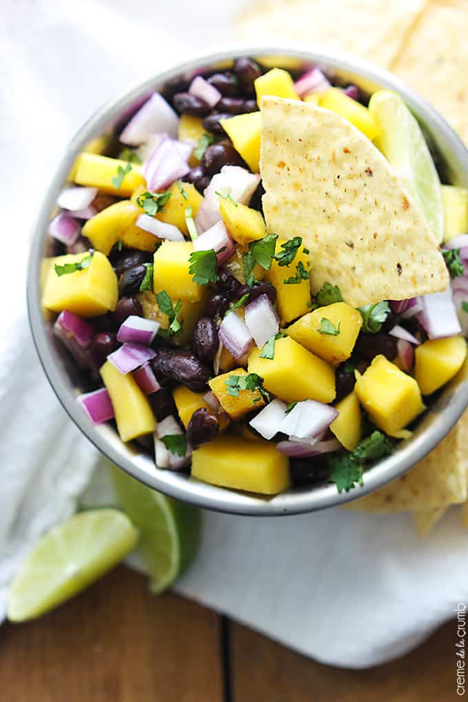 top view of mango black bean salsa in a bowl with a chip dipped in it.