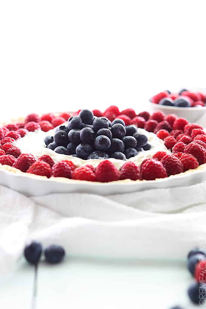 side view of mixed berry tart in a serving dish with berries on the side.