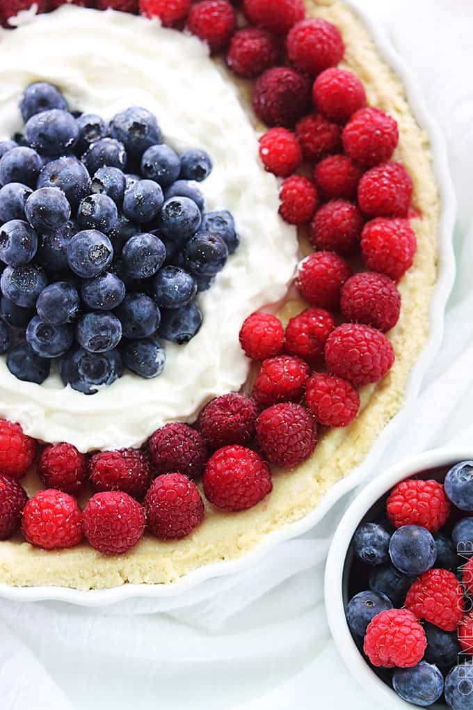 close up top view of mixed berry tart in a serving dish with berries in a bowl on the side.