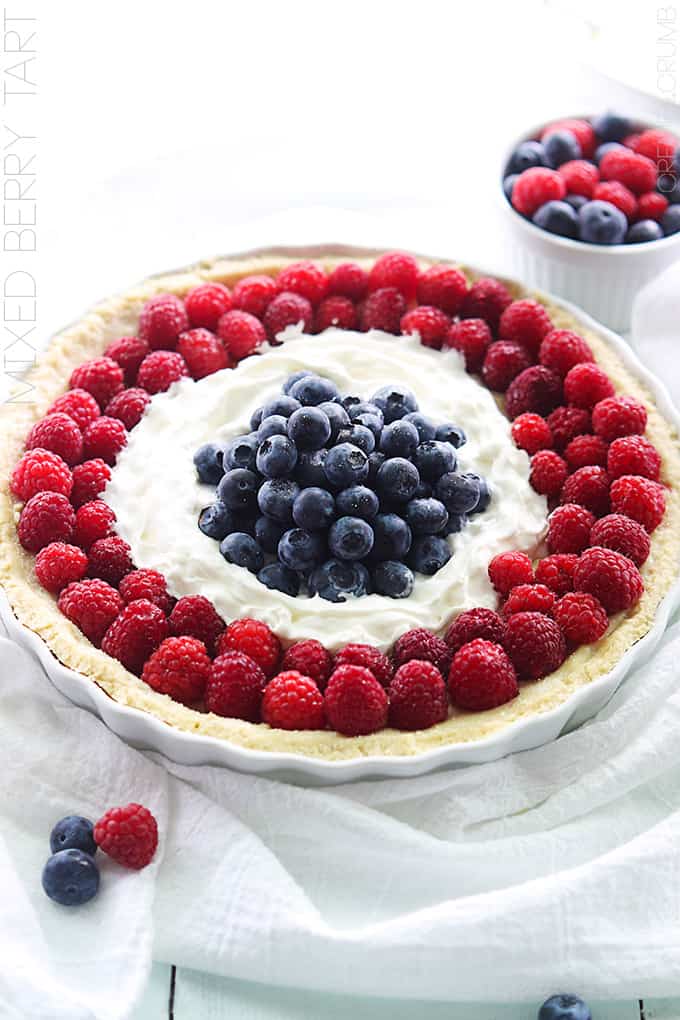 mixed berry tart in a serving dish with the title of the recipe written vertically on the left side of the image.