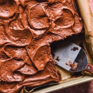Close up overhead of Dr. Pepper cake in a cake pan with a piece missing.