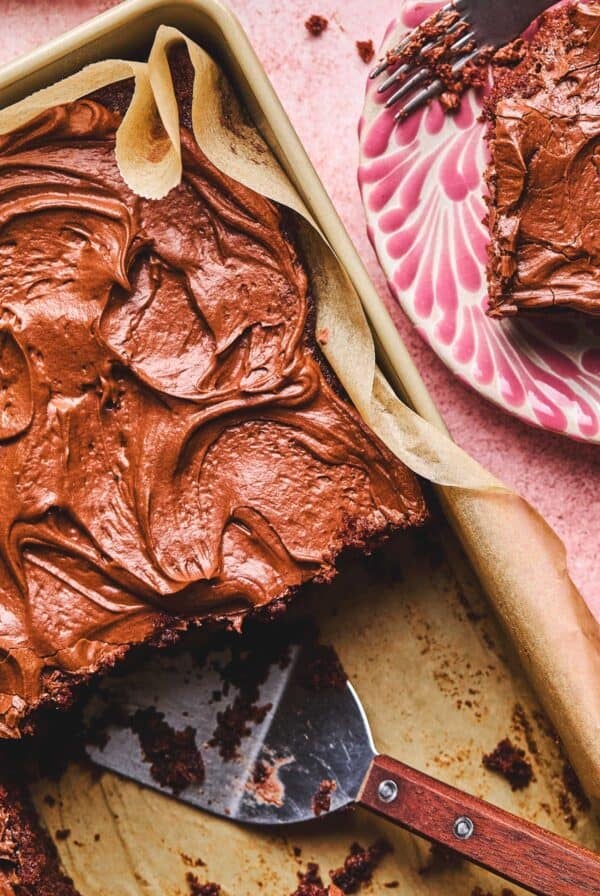 Close up overhead of Dr. Pepper Cale on a cake pan with a spatula where missing pieces are with a slice of cake on a plate next top it.