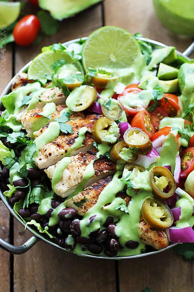 close up top view of grilled chicken taco salad with spicy cilantro lime dressing in a metal bowl.