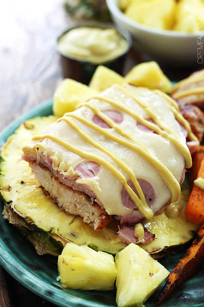 grilled Malibu chicken with a bite missing on half of a pineapple on a plate with pineapple chunks and sweet potato fries.
