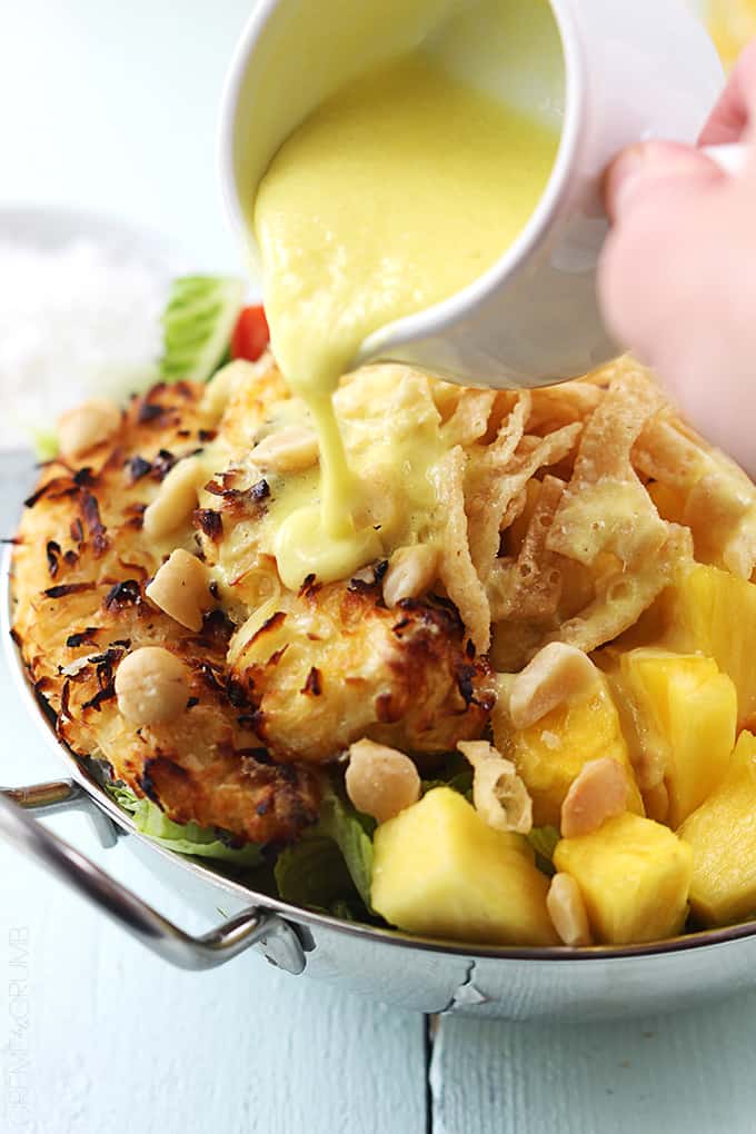 a hand pouring Pina Colada vinaigrette on Pina Colada chicken salad.