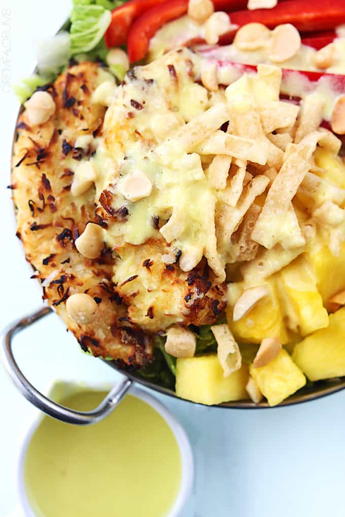 close up of Pina Colada chicken salad in a metal bowl with Pina Colada vinaigrette in a small bowl on the side.