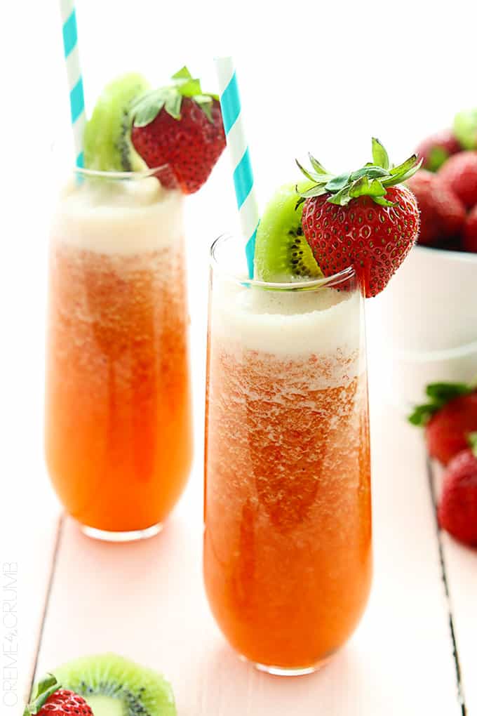 two glasses of strawberry kiwi lemonade with straws and a slice of kiwi and a whole strawberry on the top.