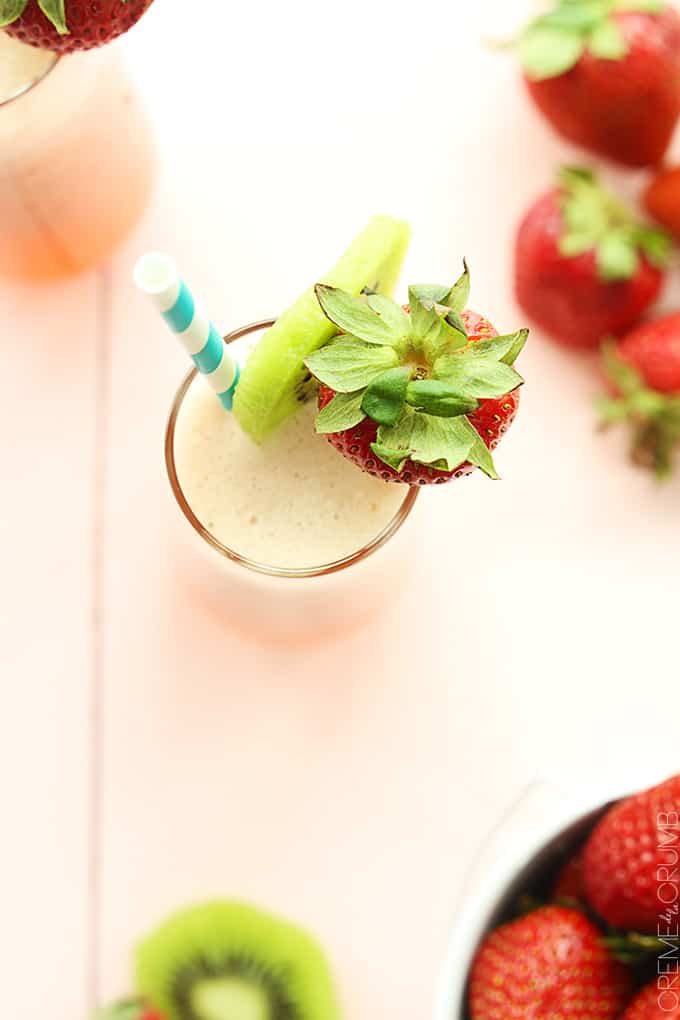 top view of strawberry kiwi lemonade in a glass with a slice of kiwi and a whole strawberry on the top of the glass with a straw.