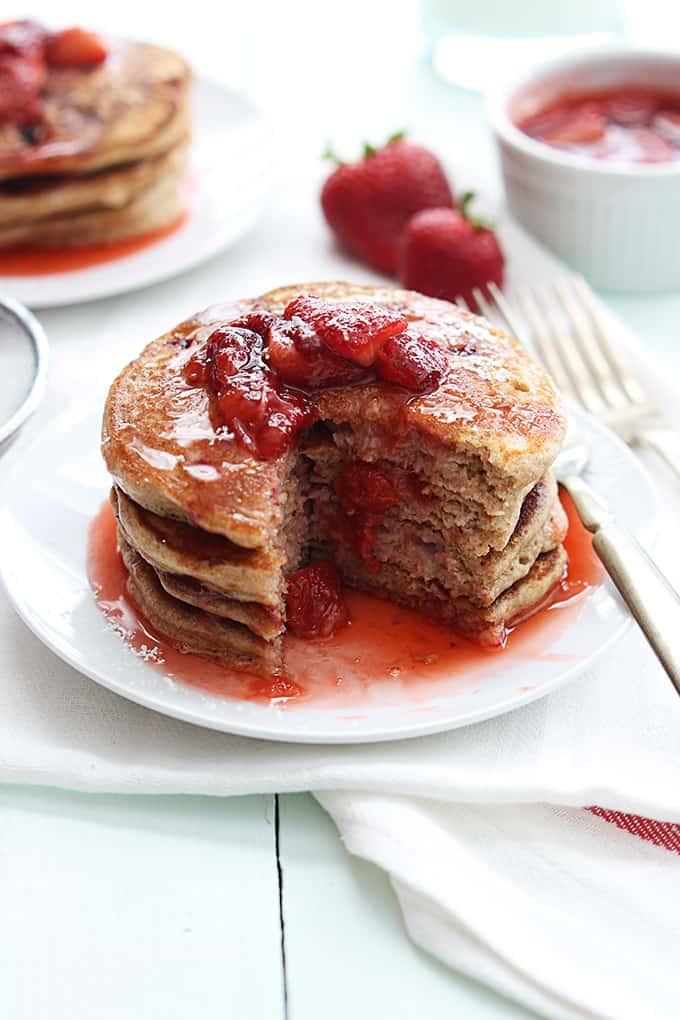 a stack of whole wheat strawberry pancakes on a plate with some of the pancakes missing.