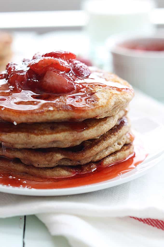 close up of a stack of whole wheat strawberry pancakes on a plate.
