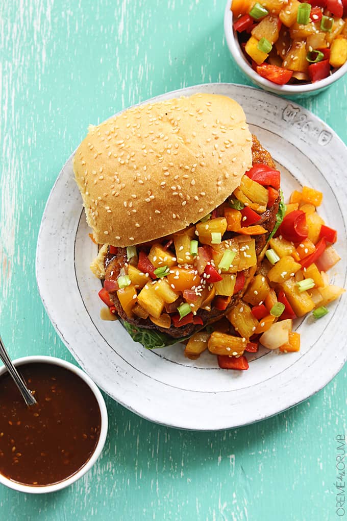 top view of an an aloha chicken sandwich on a plate with pineapple salsa and sauce in bowls on the side.