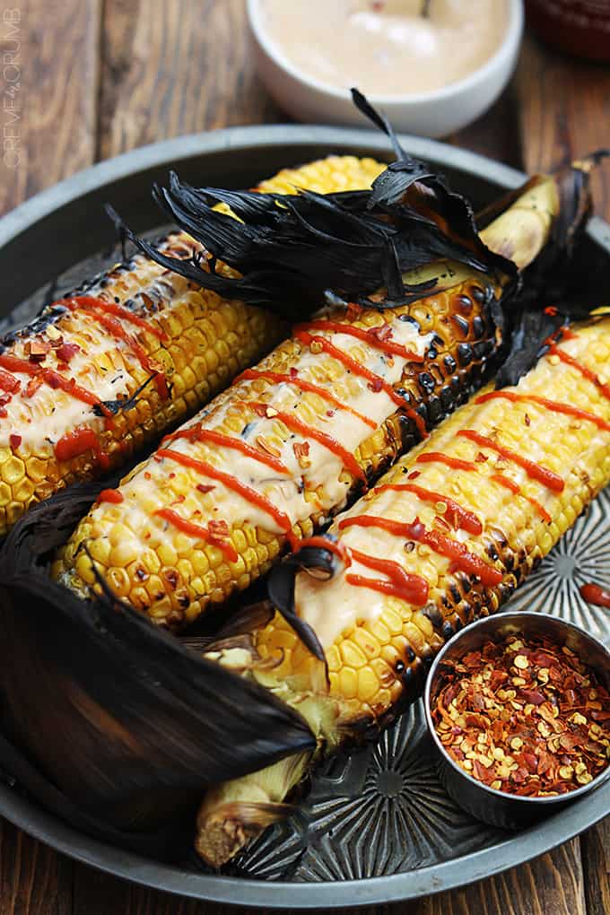 Asian grilled corn on a serving tray with seasoning in a small bowl on the side.