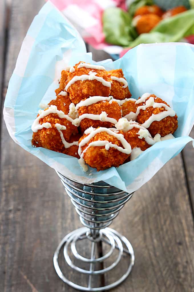buffalo popcorn chicken with sauce on top in a wired cone shaped basket.