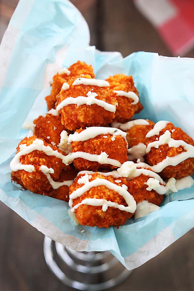 top view of buffalo popcorn chicken with sauce on top in a wired cone shaped basket.