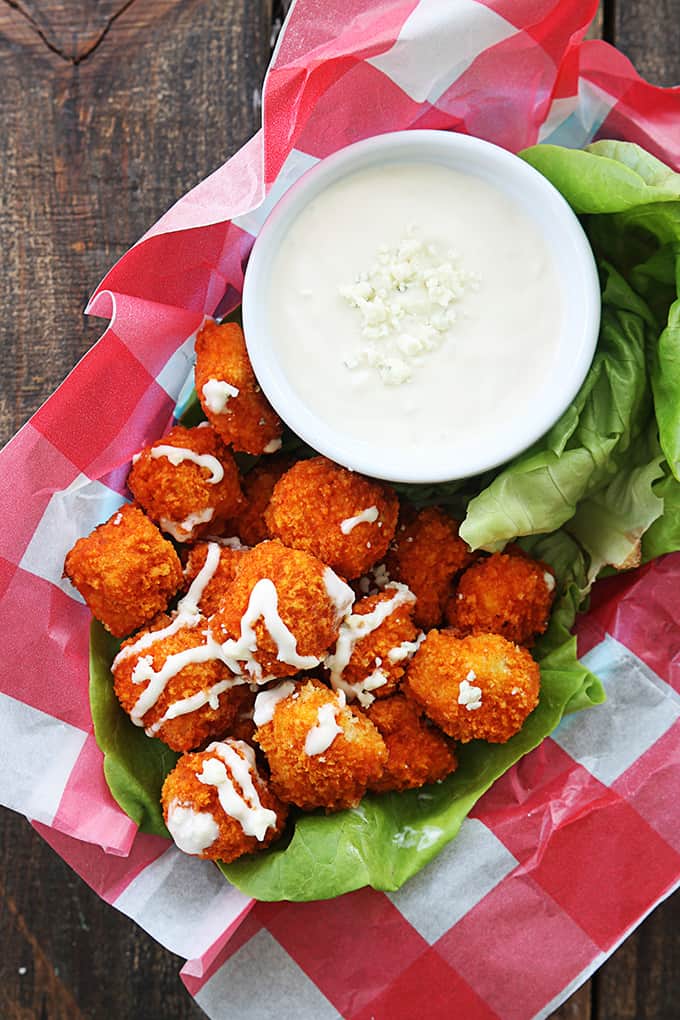 top view of buffalo popcorn chicken with sauce on top with more sauce in a bowl on the side in a basket.