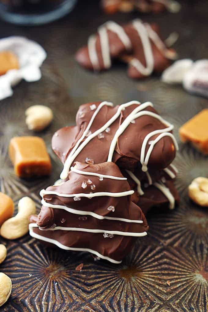 stacked caramel cashew clusters surrounded with more clusters, pieces of caramel and cashews.