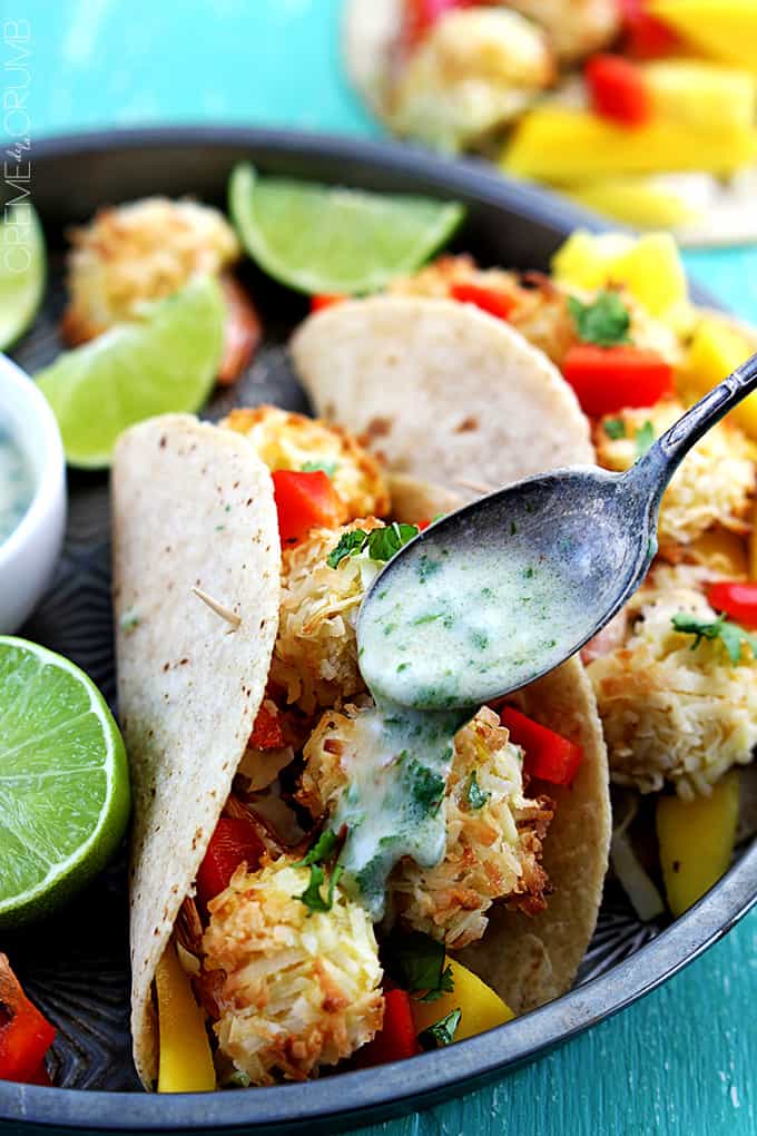 coconut shrimp tacos with a spoon pouring sauce top.