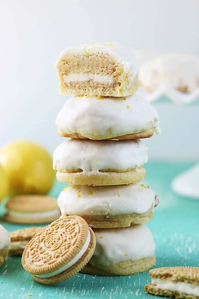 stacked golden Oreo stuffed lemon cookies with half of a cookie on the top surrounded by golden Oreos and a lemon.