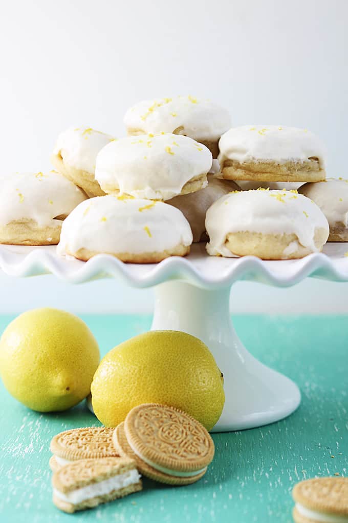 golden Oreo stuffed lemon cookies on top of a pedestal cake stand with lemons and golden Oreos around it.