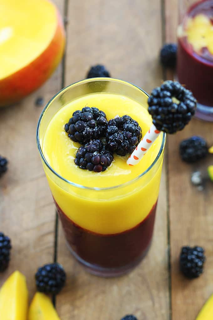 top view of a mango blackberry smoothie in a glass with blueberries and mango slices on the table.