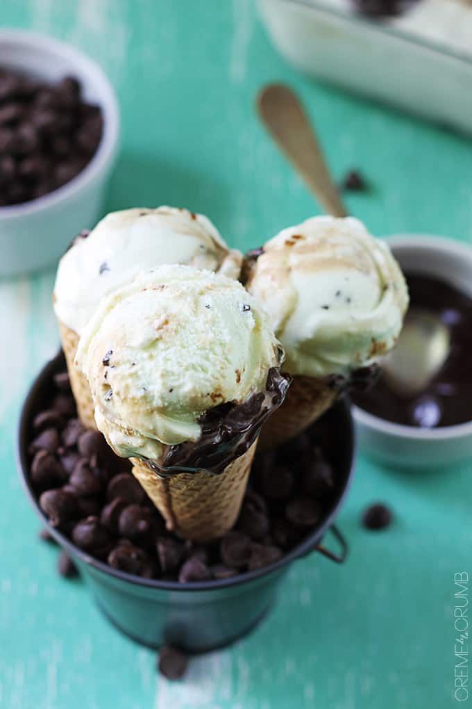 top view of hot fudge ripple mint chocolate chip ice cream cones in a metal tin with chocolate chips  and chocolate sauce faded on the side.