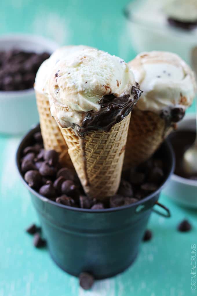 close up of hot fudge ripple mint chocolate chip ice cream cones in a metal tin with chocolate chips.