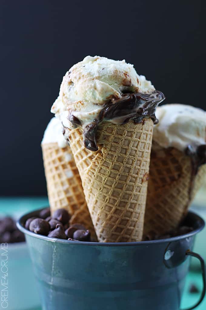 side view of hot fudge ripple mint chocolate chip ice cream cones in a metal tin full of chocolate chips.