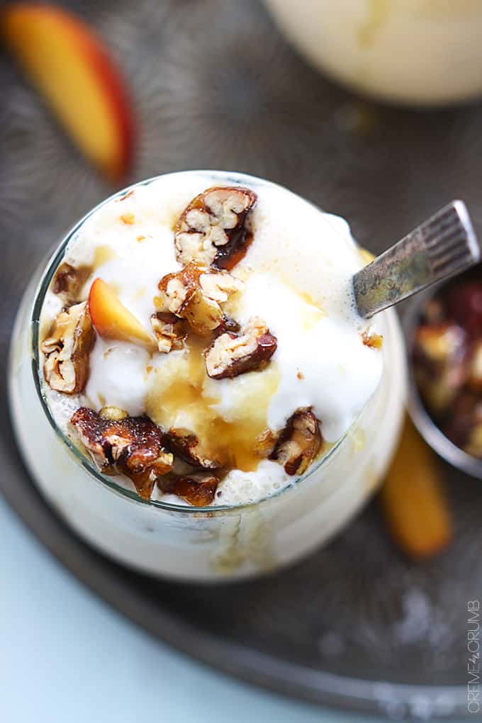 top view of a peaches n' cream caramel pecan milkshake in a glass with a spoon.