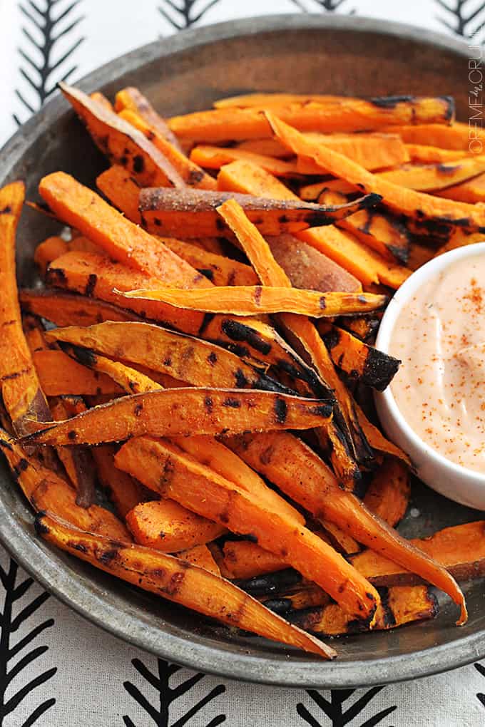 spicy grilled sweet potato fries with fry sauce on a metal tray.