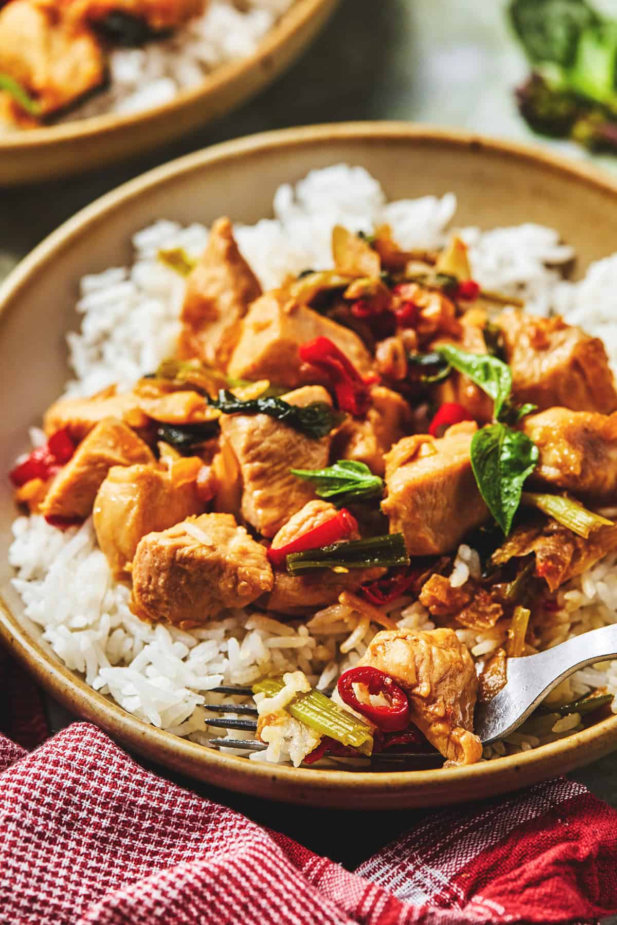 thai basil chicken in a bowl over rice with fork.