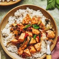 overhead view of one whole and one partial bowl of stir fry chicken with basil over rice.