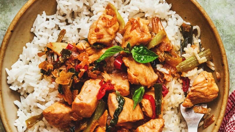 overhead view of one whole and one partial bowl of stir fry chicken with basil over rice.