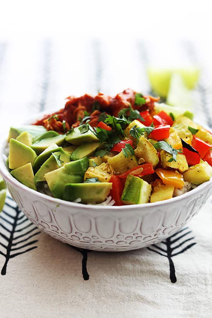 slow cooker adobo chicken with veggies and a slice of lime on top of rice in a bowl.