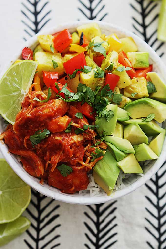 top view of slow cooker adobo chicken with veggies and a slice of lime on top of rice in a bowl.