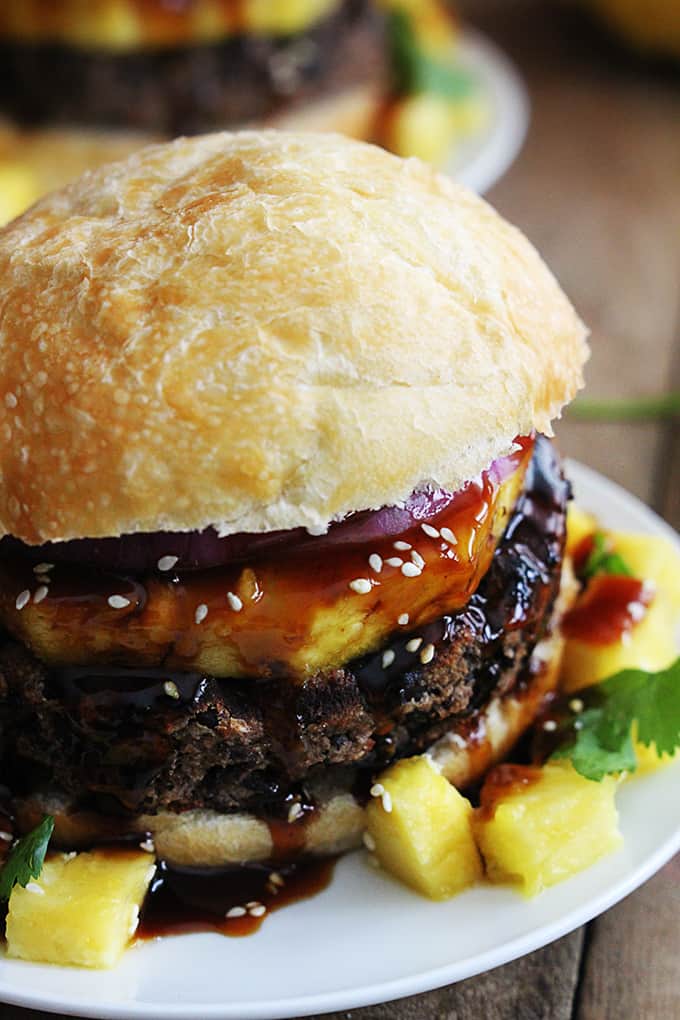 close up of a black bean teriyaki burger on a plate with another burger on a plate faded in the background.