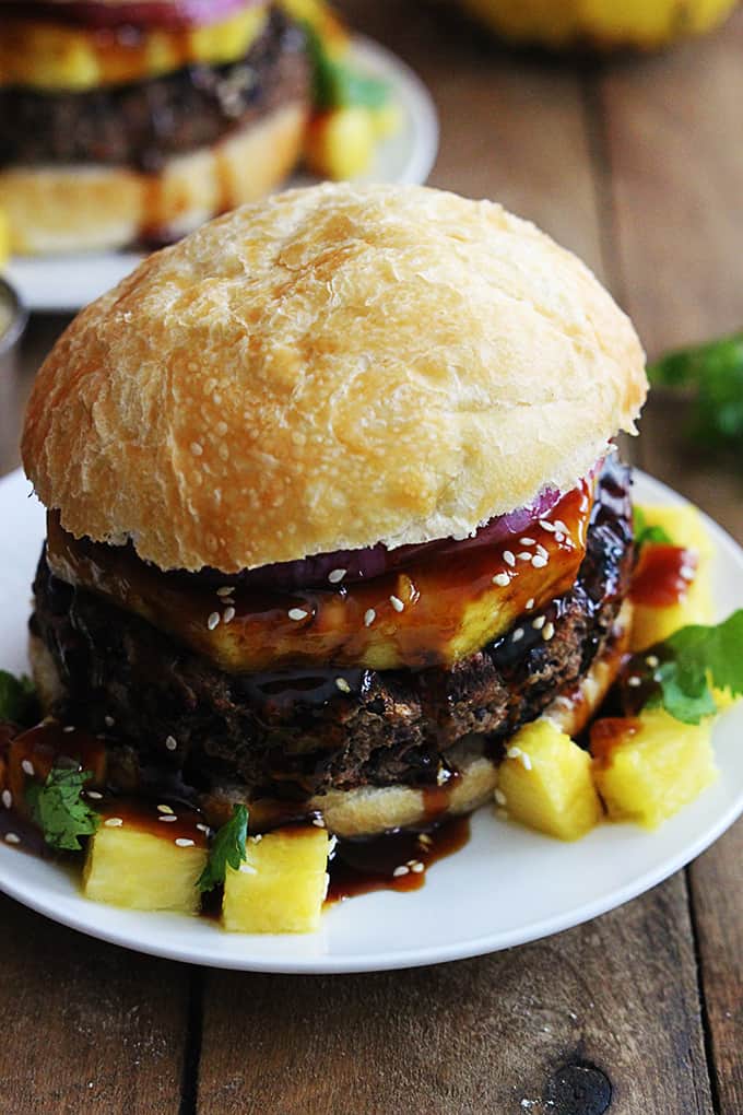 a black bean teriyaki burger on a plate with another burger on a plate in the background.